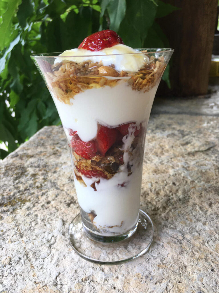 Breakfast granola - layers of natural greek yoghurt, crunchy ginger granola and fresh fruit on top.